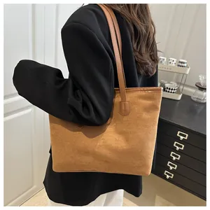 Brown suede tote bag worn by a model in a minimal interior, highlighting the large size