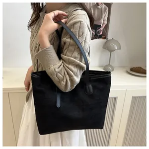 Detail view of large black faux suede tote bag on a model for daily commuting style