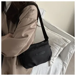Detailed view of black nylon crossbody bag with logo patch and multi-zipper compartments