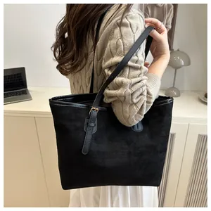 Detail view of large black suede tote bag with adjustable strap and gold buckle
