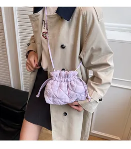 Detail of lavender quilted drawstring bucket bag with rhombus texture on beige coat