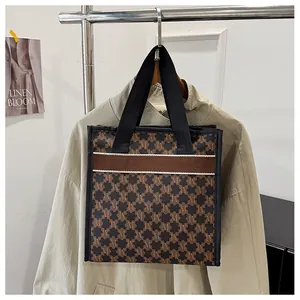 Detail of large printed tote bag with retro monogram pattern on a fashion display