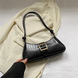 Classic black baguette bag with crocodile texture and gold metal buckle on beige blazer