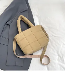 Detail of khaki quilted puffer shoulder bag featuring thick handles and pink woven strap