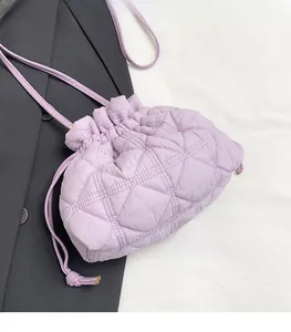 Detailed close-up of quilted lavender drawstring bucket bag on a black blazer background