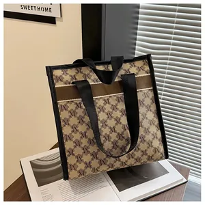 Close-up of canvas tote bag with brown monogram pattern and functional dual straps