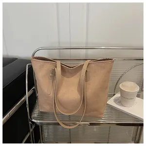 Macro shot of large khaki suede tote bag on metal cart with adjustable strap details