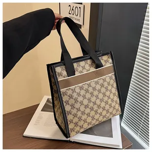Close-up of a large tote bag with M monogram print and durable black leather trim