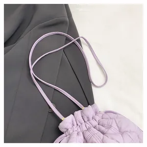 Detail of light purple quilted puff bucket bag with drawstring and golden hardware