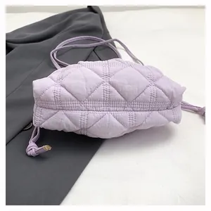 Detailed view of lavender quilted puffer bag with drawstring knot strap on grey blazer