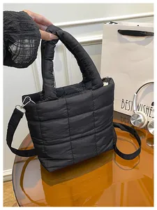 Detail of black quilted puffer bag with thick handles and detachable crossbody strap
