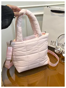 Detail of pink quilted tote bag showing embroidered grid pattern and silver hardware