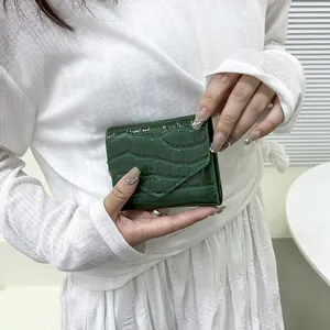 Portafoglio a tre ante in vernice verde scuro con motivo coccodrillo tenuto da una modella