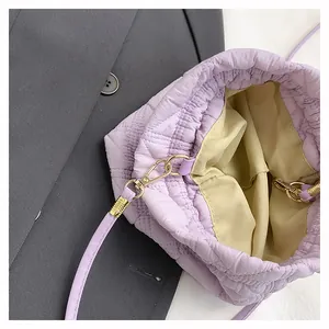 Close-up of lilac quilted bucket bag featuring drawstring closure and gold metal hardware