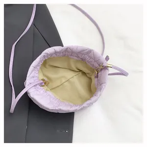 Close-up of lilac quilted drawstring bucket bag with beige lining and gold metal hook