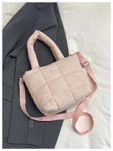 Detail of light pink quilted nylon tote bag with square stitching and adjustable strap