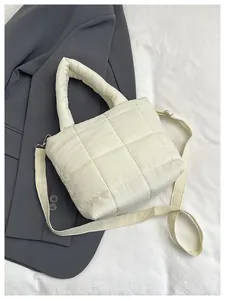 Detail of white quilted puffy handbag showing grid texture and metal shoulder strap hooks