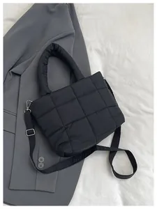 Detail of black quilted shoulder bag with soft padded handles and silver metal hardware