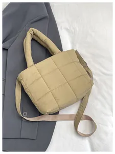Detailed macro shot of beige quilted puffer tote bag with adjustable strap on grey blazer