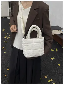 Side view of white quilted puffer tote bag with adjustable strap worn by a female model