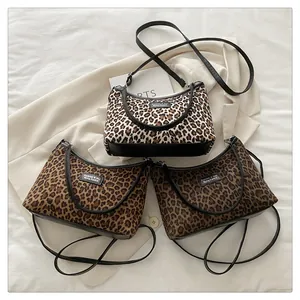 Detailed view of three leopard print crossbody bags in various tones on white fabric
