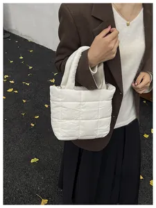 White quilted tote bag with checkered stitching shown as a shoulder bag in autumn street view