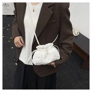 Detail of white quilted drawstring cloud bag showing soft puff texture and shoulder strap