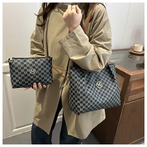 Detail of printed tote bag and pouch set with brown leather straps and gold metal logo
