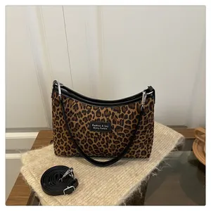Macro detail of leopard print fabric bag with black leather handle and adjustable strap