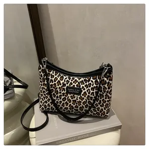 Dettaglio della borsa leopardata con cinturini in pelle nera ed etichetta del brand