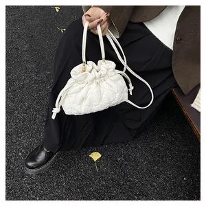 Detailed view of a white quilted drawstring cloud bag carried by a model outdoors
