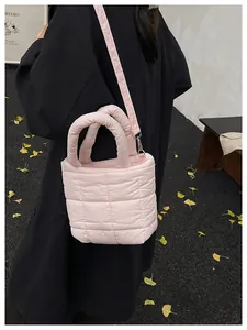 Pink quilted shoulder bag with detachable strap shown on a model in a black trench coat