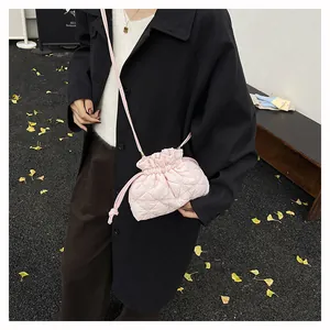 Detail of pink quilted drawstring bucket bag on a model wearing a black trench coat