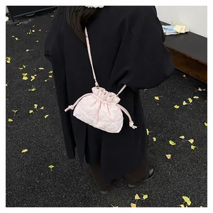Detail of pink quilted drawstring bucket bag styled with a black coat in a fall setting