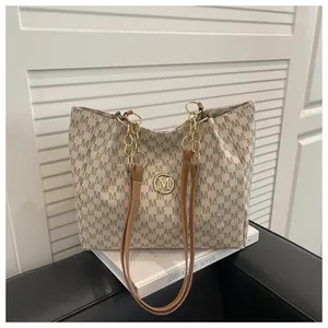 Macro shot of M-letter print texture and golden circular metallic logo on beige tote bag