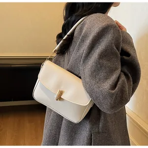Close-up of cream leather crossbody bag with elegant gold clasp and chain on model
