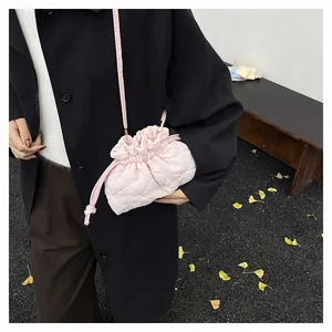 Detail of light pink quilted drawstring bag with puffer texture on black coat background