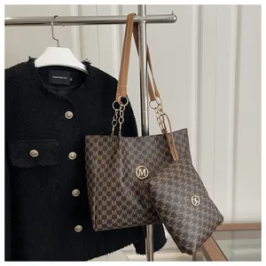 Dettaglio del set borsa tote con logo M dorato e catena su una giacca di tweed