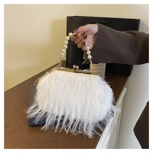 Dettaglio della borsa in peluche bianca con manico di perle e chiusura in metallo dorato