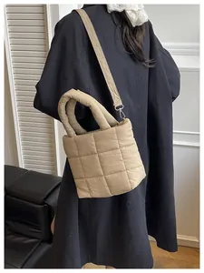 Detail of khaki quilted puffer bag showing square stitching and detachable shoulder strap