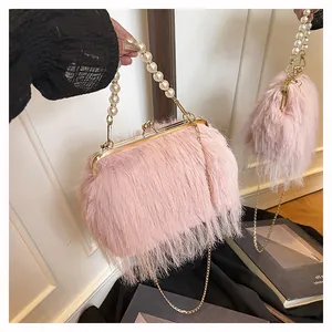 Dettaglio borsa di peluche rosa con manico di perle e chiusura dorata su uno specchio