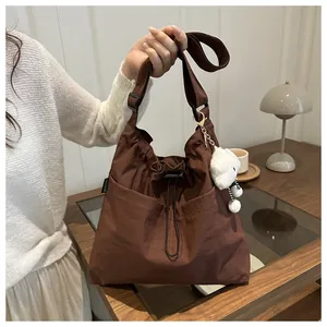 Detail of dark brown drawstring canvas bag with fashion label and plush bear charm