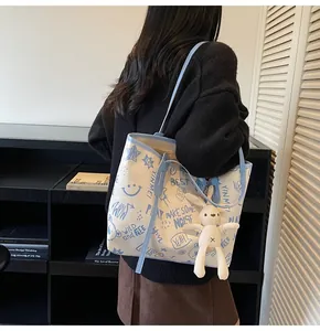 Detail of canvas tote bag with blue graffiti prints and a cute plush rabbit pendant