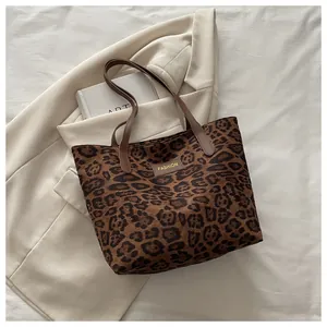 Detail einer Leopard-Print-Einkaufstasche mit braunen Riemen und modischem Etikett-Design