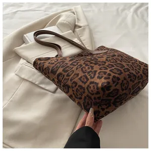 Detail der Leoparden-Einkaufstasche mit braunen Ledergriffen auf beigem Blazer-Hintergrund