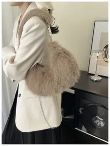 Close-up of khaki plush crescent bag with silver chain strap on a stylish woman
