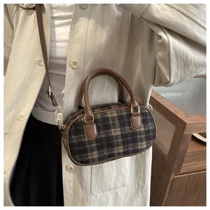 Detail of checkered woolen crossbody bag with brown leather trim and gold hardware