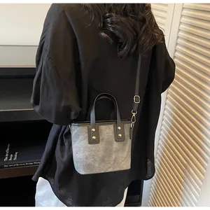 Close-up of vintage grey bucket bag with black handles and gold stud details on a model