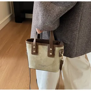 Detail of olive canvas tote with brown leather handles and adjustable shoulder strap
