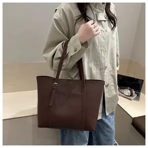 Macro detail of dark brown leather tote bag showing adjustable gold buckle and side pocket